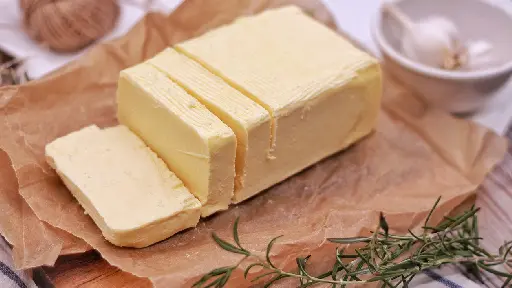 A piece of butter sitting on top of wax paper.