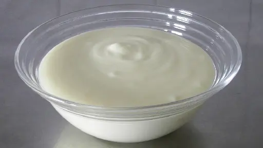 A bowl of yogurt on top of a table.