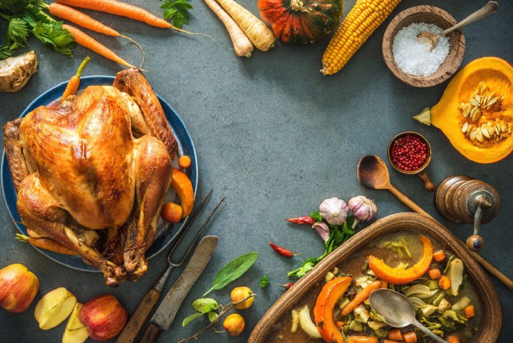 A table with turkey, vegetables and other food.