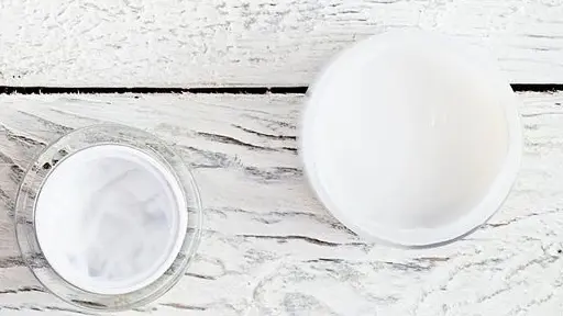 A white table with two cups and one cup of water.